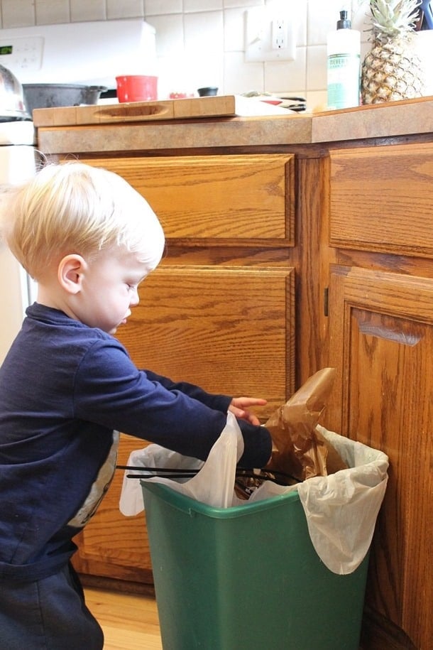 Toddlers learning to clean up and engage with foods by throwing away garlic peels.