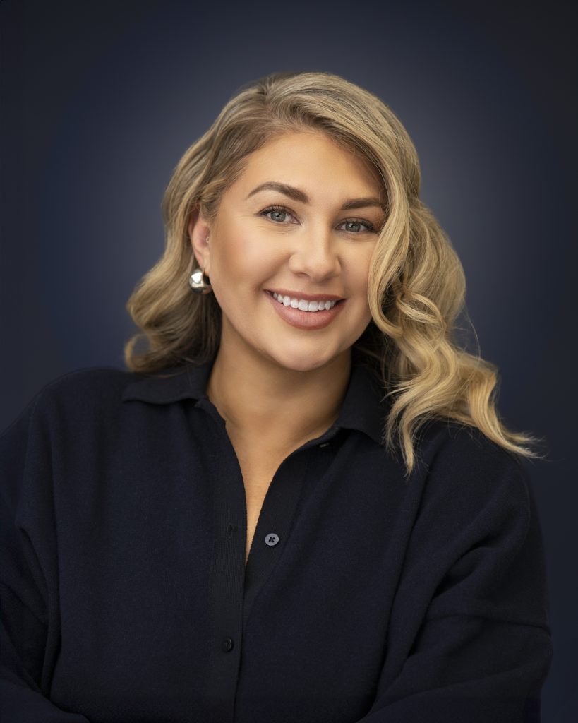 Headshot of Latina woman, with Blond Hair on a blue artistic background.